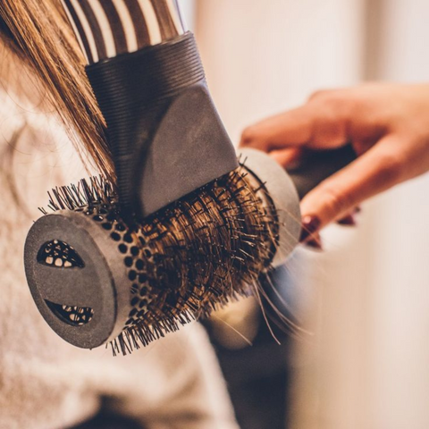 Round brush blow-drying a section of hair close up