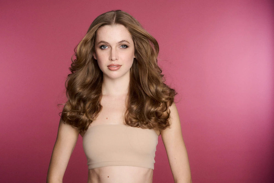 Model with voluminous salon-style curls against a pink studio backdrop