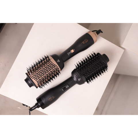 Two TNS blowout brushes with oval bristle barrels on a white plinth