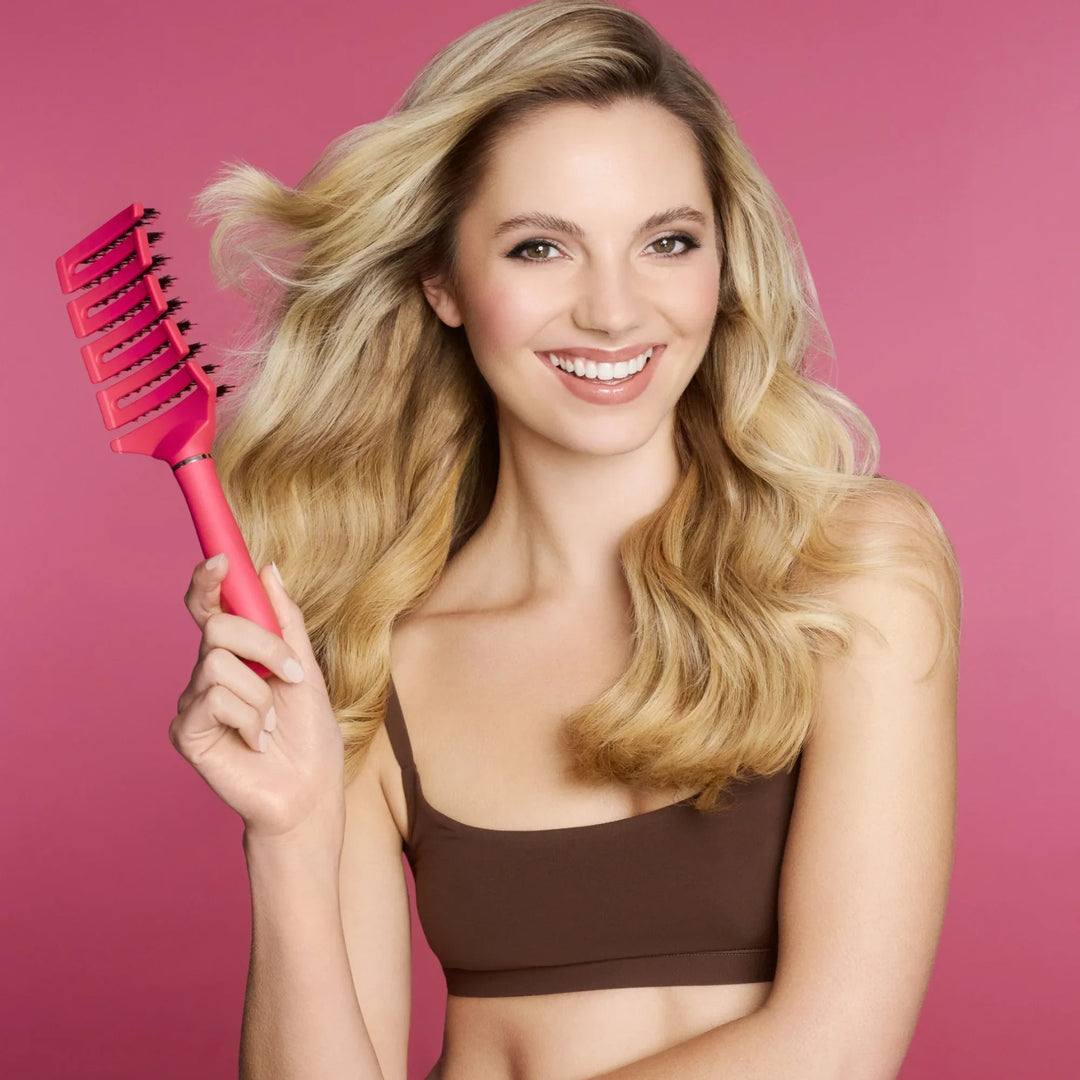 Smiling model with thick blonde curls holding the free TNS Ultra Flexi brush included in the bundle